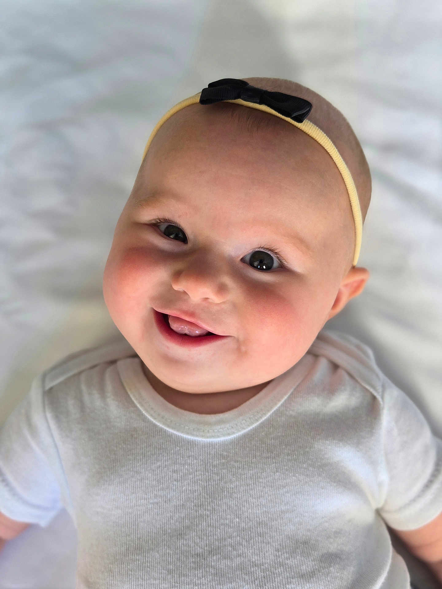Giada joined the competition — help win amazing prizes! baby, smiling, headband, white_onesie, face, infant, cute, child, portrait, closeup, lying_down, soft_light, cheeks, happy, expression, skin, eyes, mouth, tongue, background