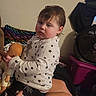 Everleigh joined the competition — help win amazing prizes! baby, child, infant, sitting, doll, toy, pajamas, stars, serious, indoor, living_room, cushion, fan, furniture, home, portrait, face, brown_hair, hands, safe