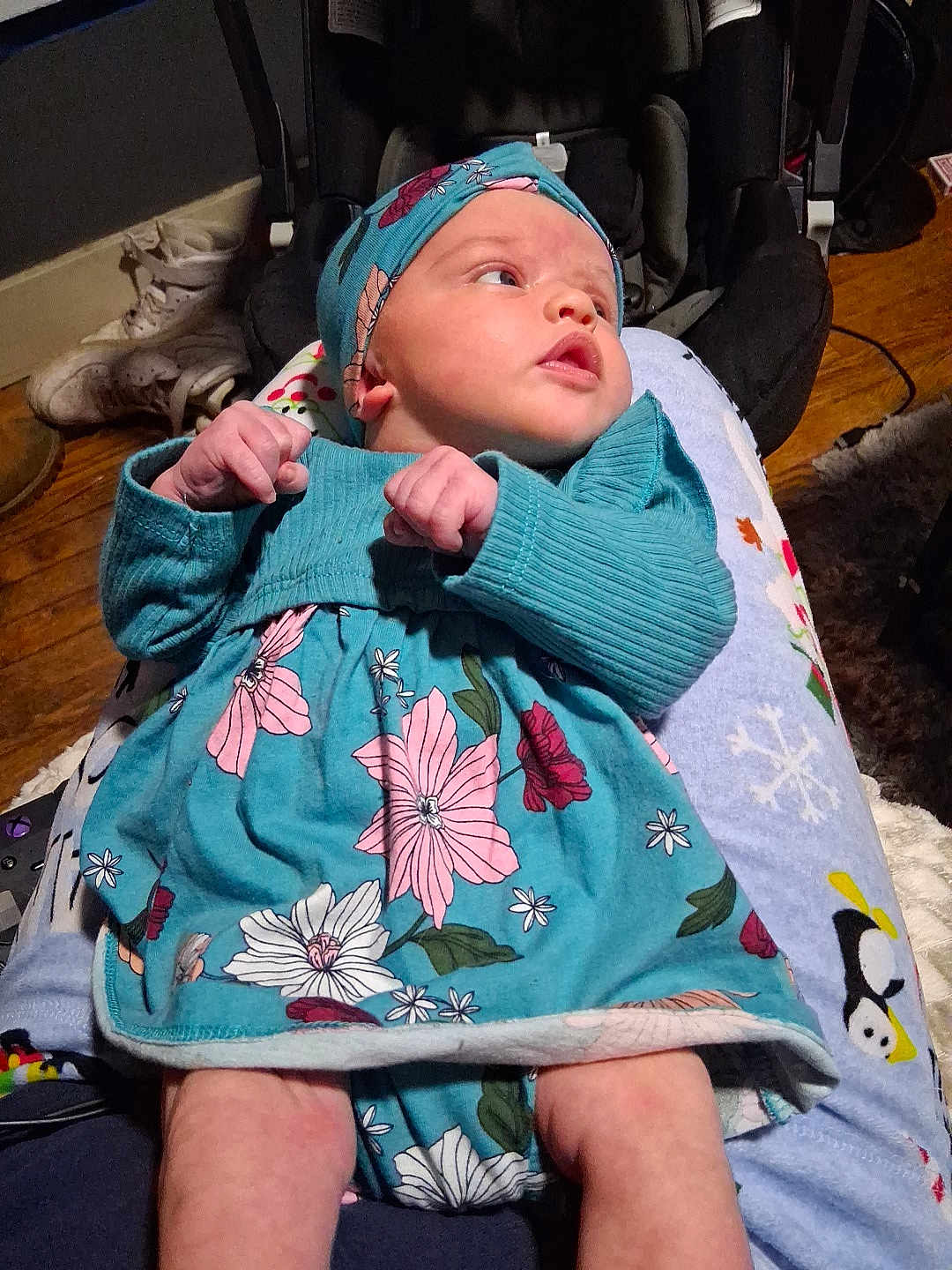 Liliana is registered to the contest to win money with this photo: baby, infant, child, floral_dress, headband, person, lap, pajamas, penguin_pattern, wooden_floor, shoes, indoor, cozy, cute, newborn, clothing, pattern, relaxing, human, portrait