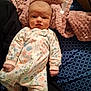 baby, infant, onesie, floral_pattern, blanket, bed, blue_sheet, pink_blanket, face, person, newborn, clothing, sleepwear, fist, expression, indoor, cute, young_child, lying_down, soft_texture