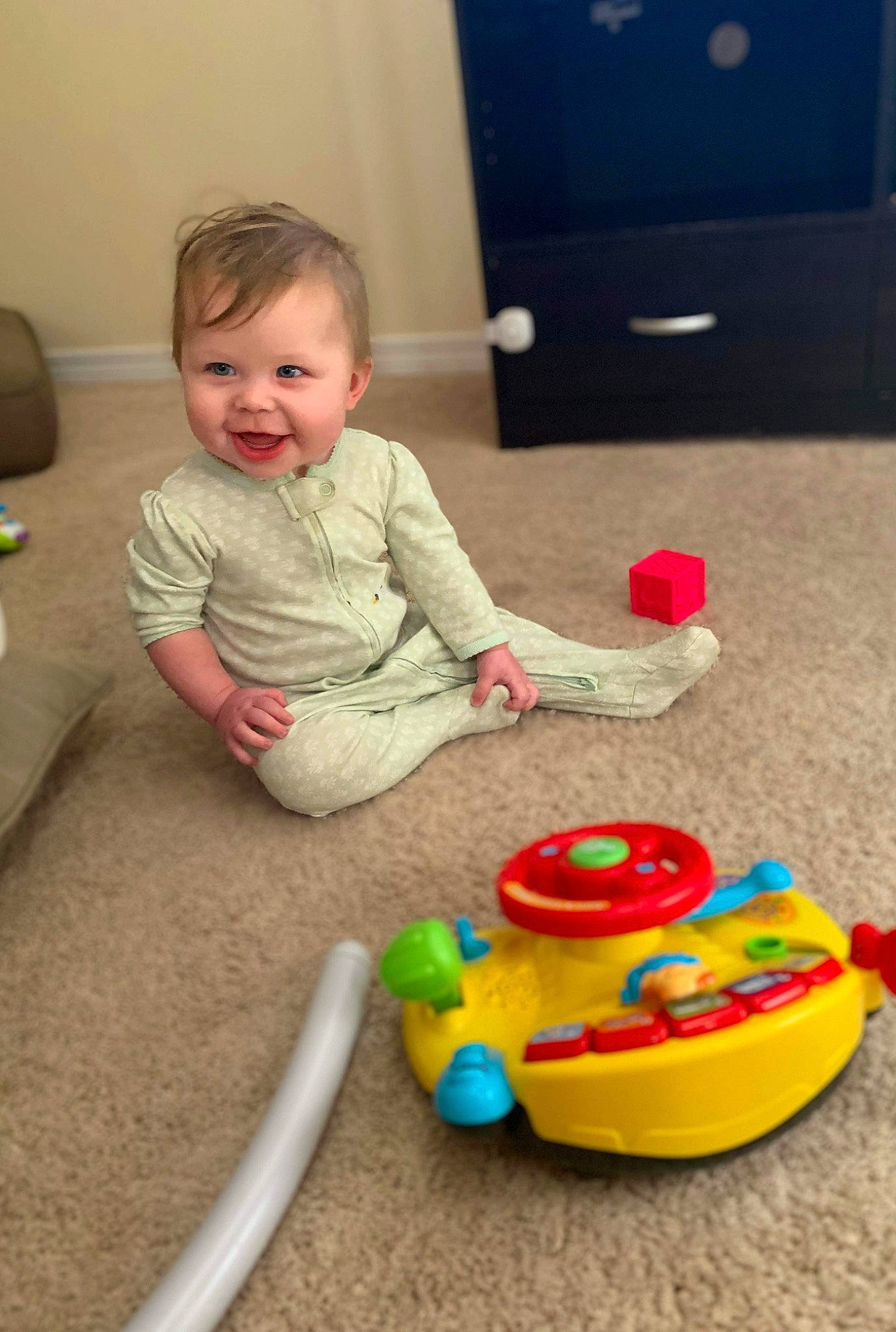 Lindsey is registered to the contest to win money with this photo: baby, baby_playing_with_toys, baby_products, baby_toddler_clothing, baby_toys, cabinetry, child, event, flooring, fun, person, plastic, play, room, sitting, smile, television, television_set, toddler, toy