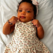 Blake is registered to the contest to win money with this photo: baby, infant, child, floral_dress, headband, pink, blanket, lying_down, cute, portrait, skin, hands, face, curly_hair, adorable, expression, soft, indoors, young, smiling