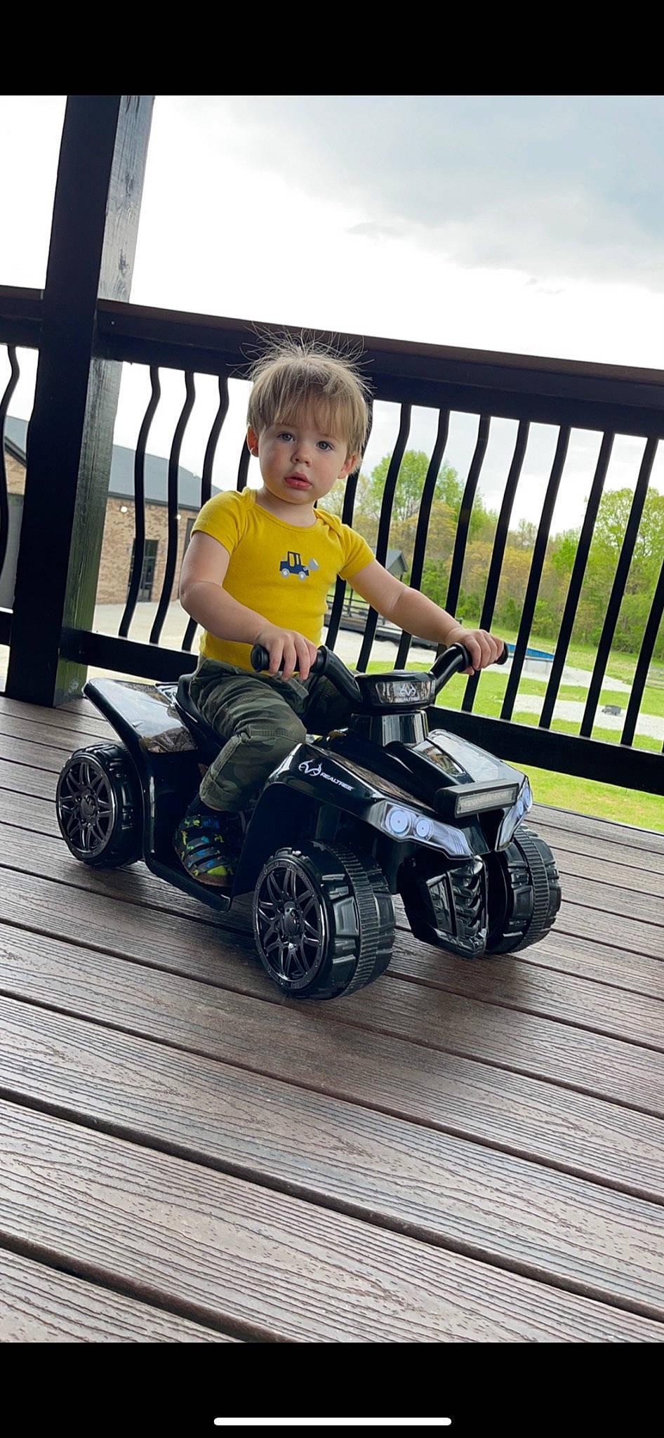 Pierre is registered to the contest to win money with this photo: automotive_design, automotive_tire, fence, fender, fun, grass, leg, motor_vehicle, person, product, public_space, riding_toy, rim, rolling, sky, synthetic_rubber, tire, toddler, tread, vehicle