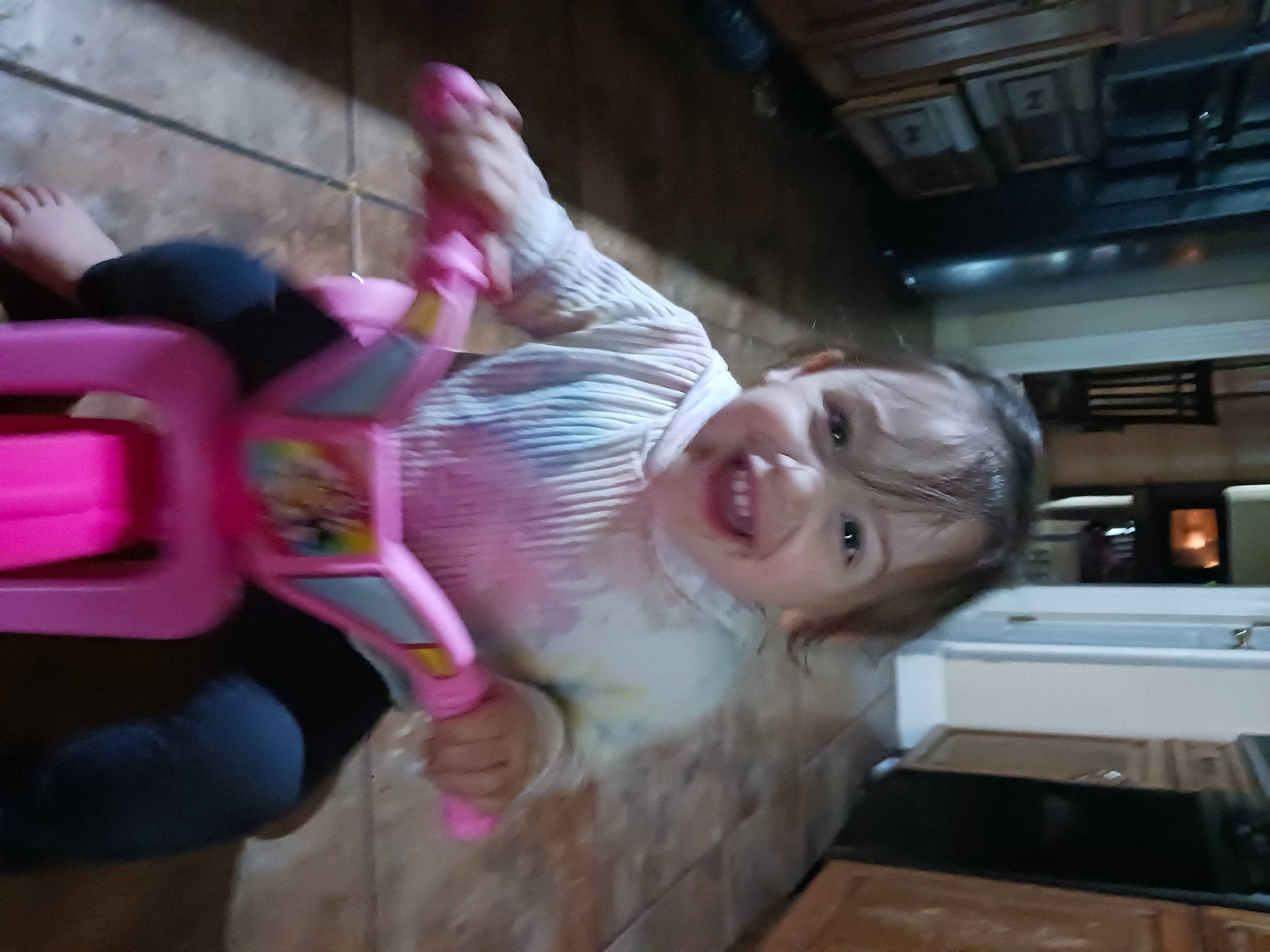 Sutton is registered to the contest to win money with this photo: baby, bangs, child, countertop, flesh, flooring, fun, gas_stove, hair_coloring, happy, home_appliance, joy, kitchen_appliance, leisure, magenta, microwave_oven, person, pink, room, smile