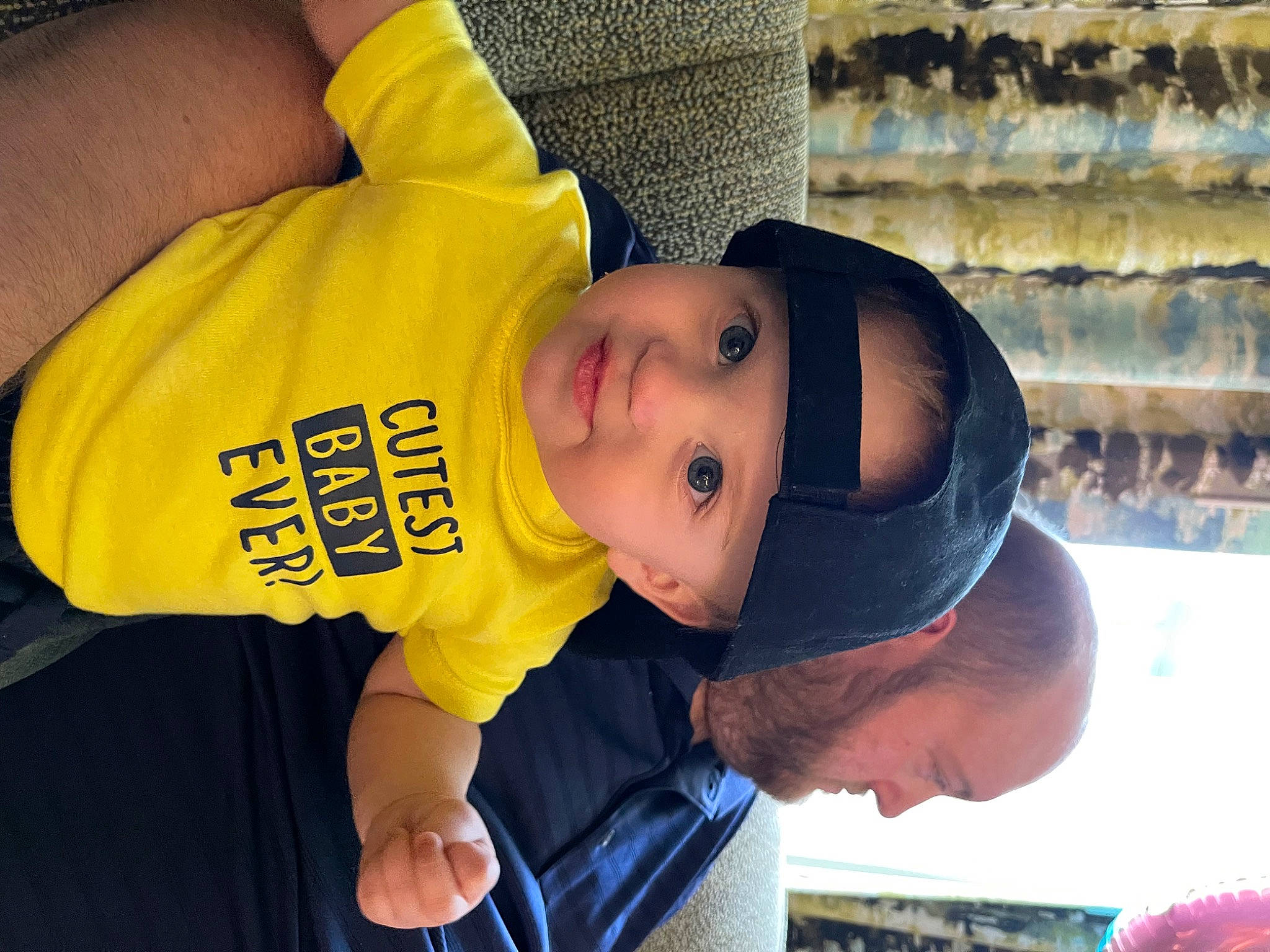 Hudson Grey is registered to the contest to win money with this photo: baby, baby_toddler_clothing, baseball_cap, cap, cheek, fun, happy, hat, headgear, headwear, leisure, people, person, photograph, room, shelf, sleeve, smile, snapshot, t_shirt
