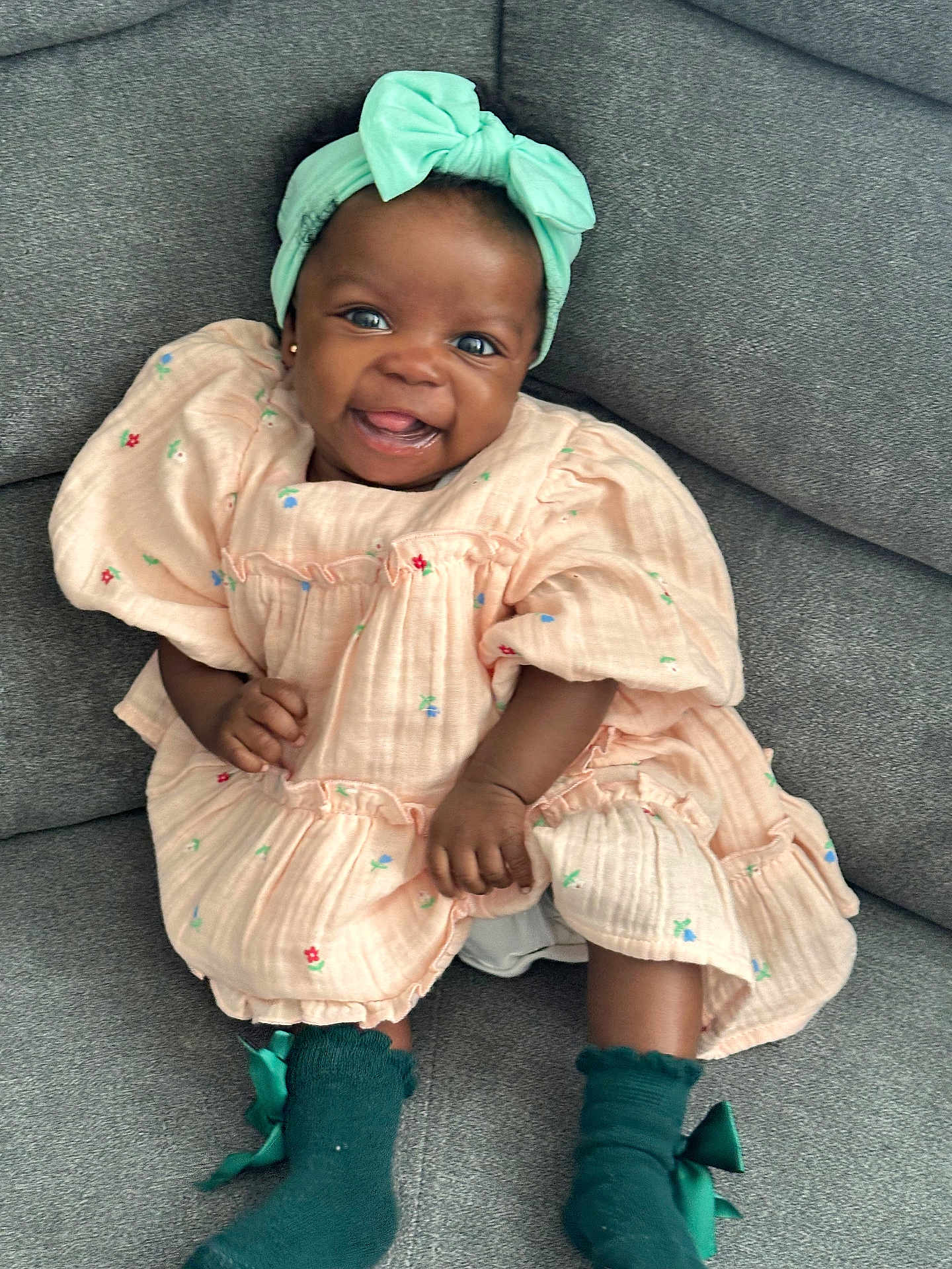 Janiyah is registered to the contest to win money with this photo: baby, child, smiling, dress, headband, bow, socks, green, peach, floral, cute, happy, sitting, couch, indoor, portrait, person, infant, fashion, apparel