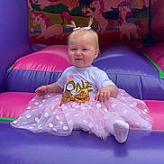 Sierra is registered to the contest to win money with this photo: baby, child, infant, toddler, birthday, party, dress, tutu, bow, pigtails, inflatable, bouncy_castle, unicorn, rainbow, outdoor, sky, cloud, grass, pink, purple
