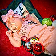 Athena joined the competition — help win amazing prizes! baby, bow, christmas_ornaments, closeup, cozy, cute, decorations, festive, headband, holiday, indoors, infant, pacifier, peaceful, pink_clothing, rainbow_ornament, red_blanket, rings, shiny_bauble, sleeping