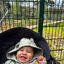 Naël participe au concours pour gagner de l'argent avec cette photo : baby, baby_clothing, baby_face, baby_hand, casual_clothing, child, cute, daylight, fence, greenery, happy, hoodie, infant, nature, outdoor, playful, portrait, smiling, stroller, sunlight
