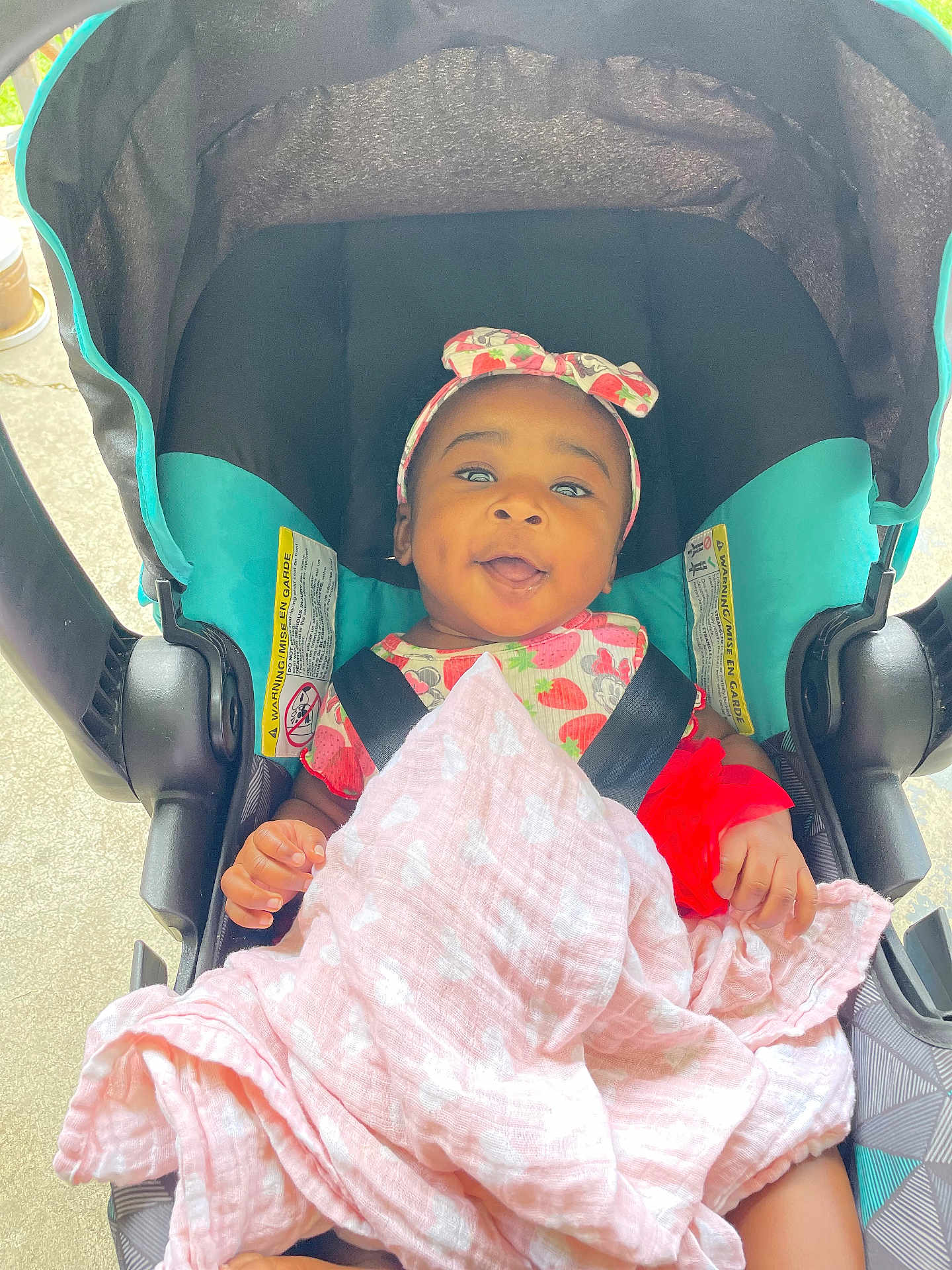 Zahrah joined the competition — help win amazing prizes! baby, child, car_seat, blanket, headband, smiling, happy, infant, clothing, seat_belt, person, cute, portrait, indoors, toddler, pink, red, pattern, face, baby_girl