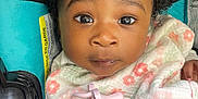 Zahrah is registered to the contest to win money with this photo: baby, child, infant, face, headband, bow, blanket, pacifier, car_seat, straps, clothing, curly_hair, expression, closeup, seatbelt, pink, white, floral_pattern, cute, indoors