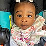 baby, child, infant, face, headband, bow, blanket, pacifier, car_seat, straps, clothing, curly_hair, expression, closeup, seatbelt, pink, white, floral_pattern, cute, indoors