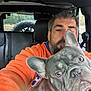 Smoke joined the competition — help win amazing prizes! man, dog, french_bulldog, vehicle_interior, selfie, orange_jacket, seat, headrest, window, tire, outdoor_background, pet, animal, companion, portrait, close_up, face, beard, casual_clothing, daylight