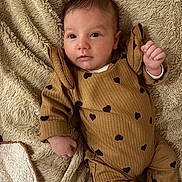 Victoire participe au concours pour gagner de l'argent avec cette photo : baby, infant, blanket, brown_outfit, hearts_pattern, cute, lying_down, soft_texture, indoors, portrait, child, small_hand, face, eyes, cozy, warm_colors, sleepwear, newborn, resting, comfortable