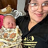 baby, newborn, infant, sleeping, parent, woman, smiling, portrait, selfie, glasses, floral_blanket, swaddled, indoor, home, furniture, clothing, cuddling, family, close_up, photography