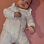 baby, infant, onesie, pink_background, lying_down, face, hand, cute, calm, child, newborn, soft_lighting, shadow, clothing, sleepwear, portrait, young_child, indoor, person, skin