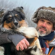 Vicky a rejoint le concours — aidez-le/la à gagner de superbes lots ! man, dog, winter_clothing, fur_hat, scarf, outdoor, cold_weather, pet, animal, portrait, holding, furry, beard, brown_eyes, black_fur, white_fur, orange_fur, nature, friendship, closeup