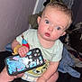 baby, infant, blue_eyes, phone_case, stitch, sitting, indoor, couch, curious, clothing, diaper, hand, foot, wall, toy, blanket, person, face, child, expression