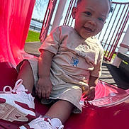 Dakari joined the competition — help win amazing prizes! toddler, child, slide, playground, outdoor, smiling, sneakers, red, beige_clothing, hair_puffs, sunny, grass, happy, park, daylight, young_child, casual_wear, play, fun, cute