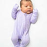 baby, newborn, child, infant, portrait, lying_down, lavender, onesie, clothing, white_background, studio_photo, face, head, arms_raised, closed_fists, sleepwear, cute, calm, solo_subject, photography
