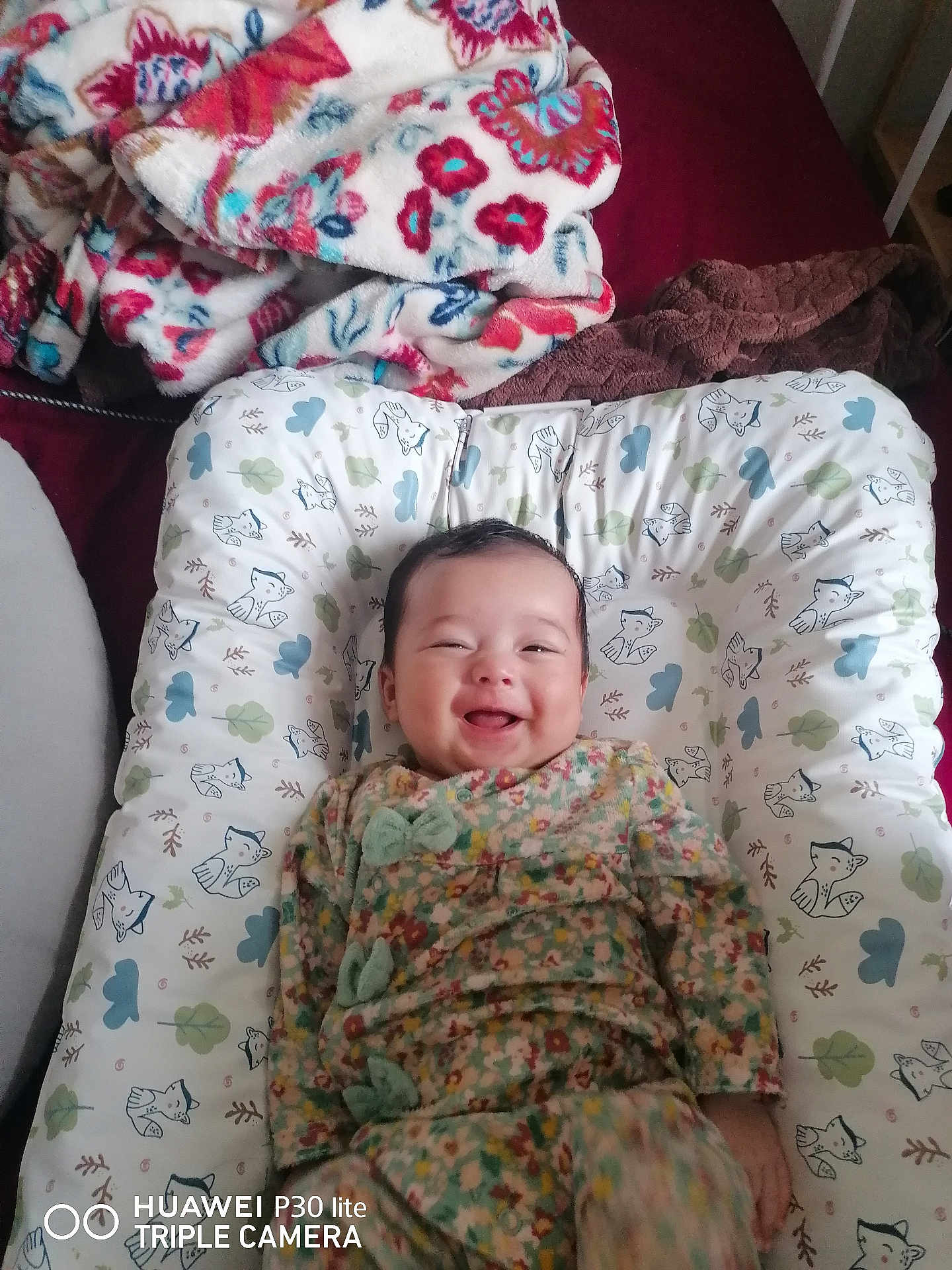 Lyana a rejoint le concours — aidez-le/la à gagner de superbes lots ! baby, smile, cushion, blanket, fox_pattern, floral_outfit, indoor, happy, child, person, bed, fabric, comfort, cute, infant, lying_down, home, soft, colorful, cozy