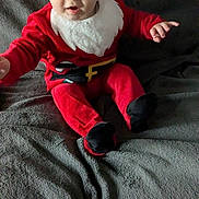 Gabriel a rejoint le concours — aidez-le/la à gagner de superbes lots ! baby, child, santa_hat, red_clothing, black_booties, blanket, indoor, holiday, festive, cute, smiling, portrait, infant, cozy, seasonal, christmas, sitting, face, person, young