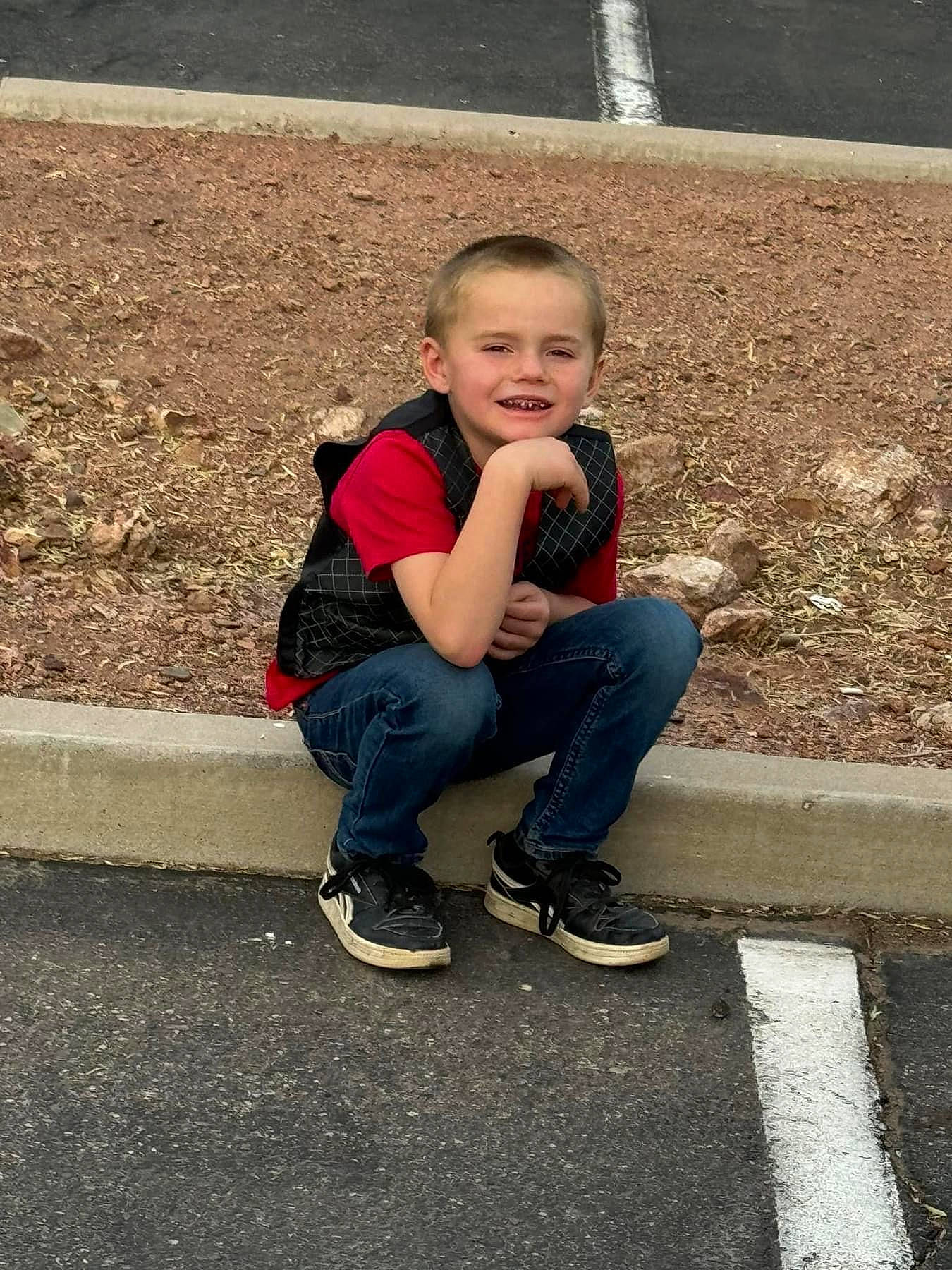 Lance is registered to the contest to win money with this photo: asphalt, child, concrete, denim, fun, grass, happy, jeans, joy, landscape, leg, leisure, person, road_surface, shoe, sitting, smile, sneakers, soil, toddler