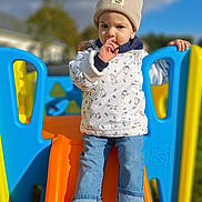 Sasha participe au concours pour gagner de l'argent avec cette photo : child, toddler, beanie, jacket, thumb_sucking, slide, playground, outdoor, blue, orange, yellow, jeans, sneakers, hand, sky, cloud, grass, daylight, person, toy
