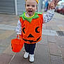 Sasha participe au concours pour gagner de l'argent avec cette photo : toddler, child, halloween_costume, pumpkin, orange, bucket, white_shoes, playful, tongue_out, hand_holding, sidewalk, urban, outdoor, person, costume, festive, cute, smiling, fall, walking
