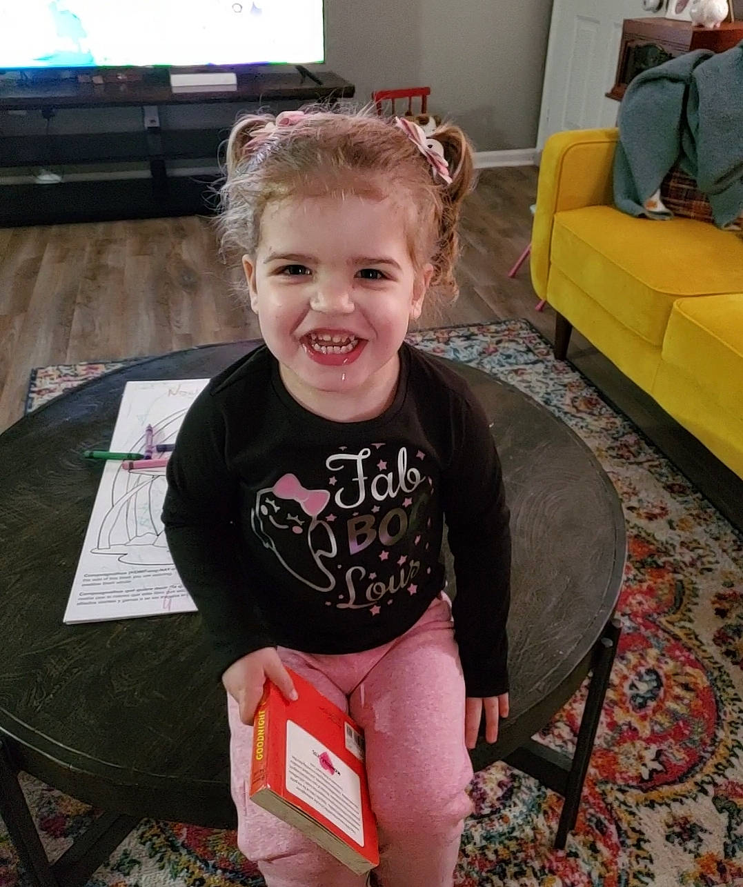 Noelle joined the competition — help win amazing prizes! baby_toddler_clothing, child, couch, facial_expression, floor, fun, furniture, hair, hairstyle, happy, head, joy, lap, living_room, person, sitting, sleeve, smile, table, television