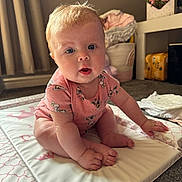 Myla-Mae is registered to the contest to win money with this photo: baby, child, infant, sitting, pink_onesie, soft_mat, curly_hair, blue_eyes, indoors, carpet, basket, flowers, folded_clothes, baby_clothing, cute, chubby_cheeks, floor, home, portrait, curious