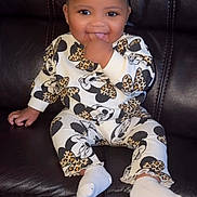 Diyani joined the competition — help win amazing prizes! baby, child, smiling, sitting, couch, leather, outfit, minnie_mouse, patterned_clothing, white_socks, happy, cute, indoor, portrait, young_child, hand_in_mouth, dark_background, small_person, fashion, cheerful