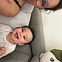 baby, woman, glasses, smile, couch, plush_pillow, happy, face, relaxing, indoor, casual, joyful, portrait, child, person, home, furniture, clothing, skin, expression