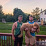 man, dog, backyard, deck, fence, grass, tree, sunset, house, playground, smile, glasses, tank_top, shorts, pet, tongue_out, outdoor, friendship, casual, nature