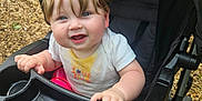 Lillith joined the competition — help win amazing prizes! baby, blond_hair, blue_eyes, casual, child, embroidery, face, foot, hand, happy, nature, outdoor, person, plastic_tray, seat, smiling, stroller, wheel, white_shirt, wood_chips