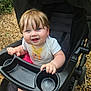 Lillith joined the competition — help win amazing prizes! baby, child, stroller, outdoor, smiling, happy, blond_hair, blue_eyes, white_shirt, embroidery, plastic_tray, wood_chips, hand, foot, face, person, nature, seat, wheel, casual
