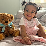 Alaiya joined the competition — help win amazing prizes! toddler, child, baby, smile, pigtails, bed, blanket, teddy_bear, plush_toy, indoors, soft_light, cute, happy, pink_clothing, person, foot, hand, cozy, curtain, window