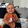 Nicole is registered to the contest to win money with this photo: baby, child, infant, toy, cushion, patterned, clothing, socks, indoor, home, cute, smile, face, hands, sitting, playful, person, soft, background, comfort
