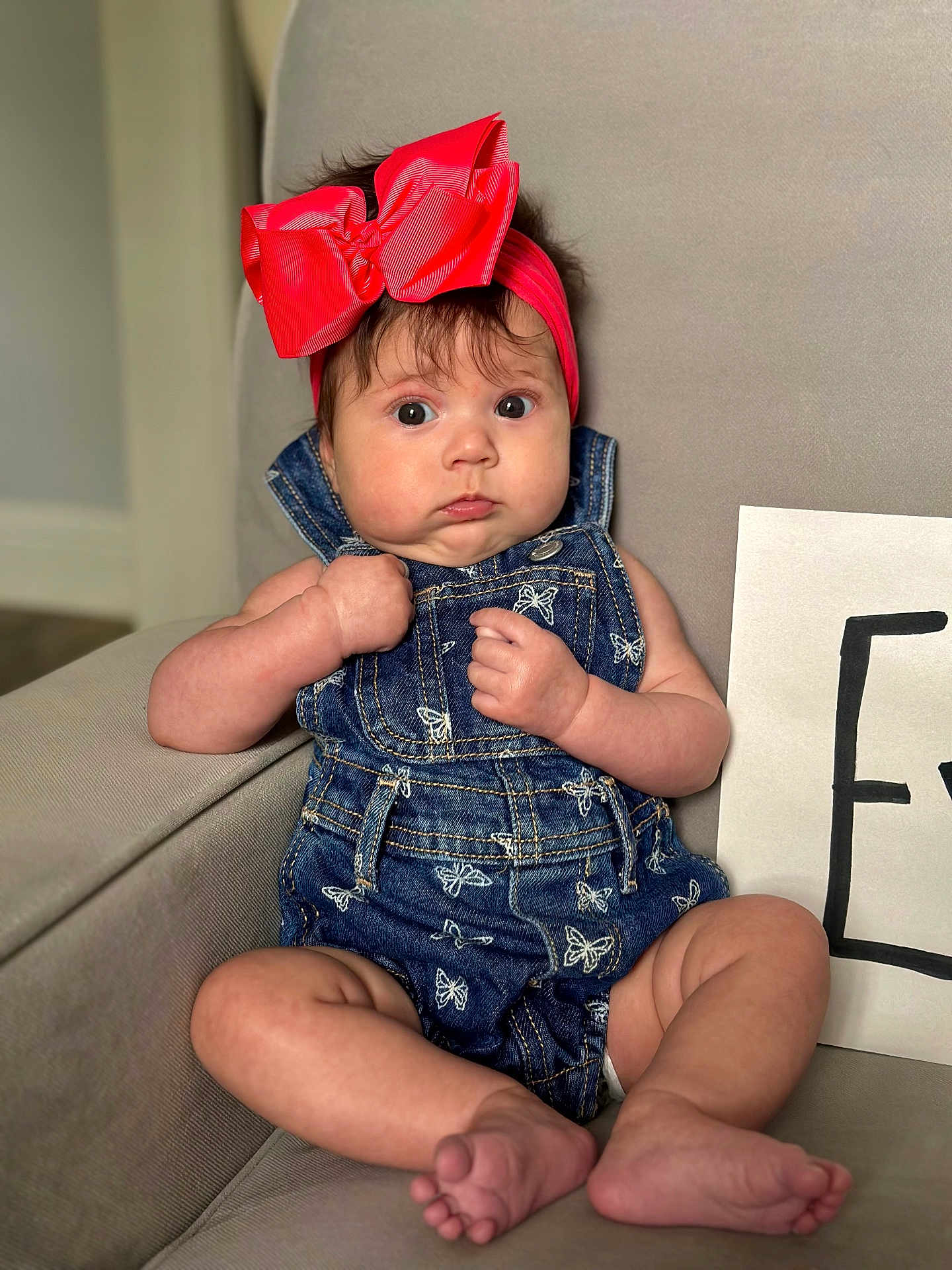Ivory is registered to the contest to win money with this photo: baby, infant, child, headband, bow, denim, overalls, butterfly_pattern, armchair, furniture, indoor, skin, face, eyes, hands, feet, clothing, cute, expression, portrait