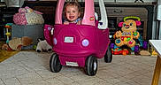 Khaleesi joined the competition — help win amazing prizes! toddler, child, smiling, toy_car, pink, playroom, indoor, television, racing_game, porsche, stuffed_animals, toys, carpet, furniture, speaker, dashboard, sitting, happy, portrait, home