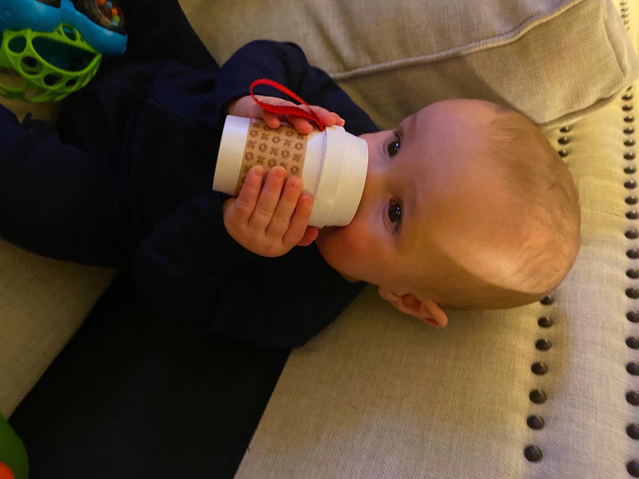 Santino is registered to the contest to win money with this photo: arm, baby, baby_bottle, baby_food, baby_products, baby_toddler_clothing, child, drinkware, finger, green, hand, head, human_body, mouth, nail, nose, person, room, thumb, toddler