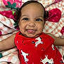 baby, blanket, cheerful, child, close_up, colorful, cute, face, happy, indoors, infant, lying_down, playful, portrait, red_clothing, smiling, soft_texture, strawberry_pattern, tongue_out, unicorn_pattern