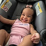 baby, baby_girl, car_seat, child, closeup, clothing, cute, hair_bow, happy, human, indoor, infant, person, pink_outfit, playful, seat, seat_belt, smiling, tongue_out, warning_label