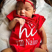 Nalani is registered to the contest to win money with this photo: baby, infant, red_onesie, headband, sleeping, blanket, soft_texture, cute, newborn, peaceful, closeup, skin, hand, legs, indoors, portrait, child, person, comfort, resting