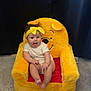 baby, child, plush_chair, winnie_the_pooh, yellow_headband, carpet, indoor, happy, smiling, seated, cute, infant, toy_chair, person, face, clothing, playful, background, fabric, curtain