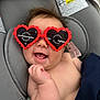 baby, sunglasses, heart_shaped, car_seat, smiling, infant, protective_film, cheeky, happy, child, clothing_tag, gray, cute, funny, casual, portrait, indoor, head, hand, seat