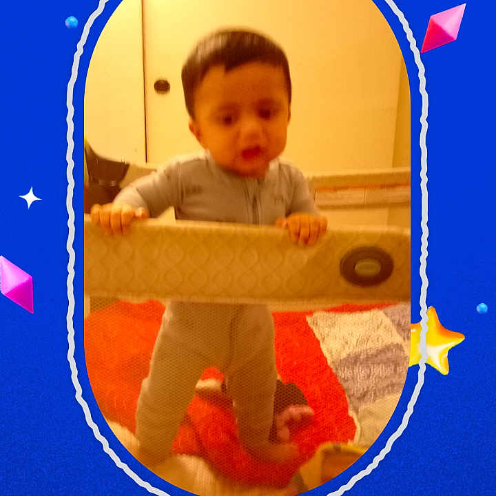 Adian is registered to the contest to win money with this photo: baby, child, toddler, standing, playpen, indoor, portrait, face, eyes, hair, curious, serious, clothing, room, carpet, toy, furniture, smartphone_screenshot, social_media, colorful