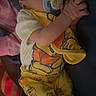 baby, sleeping, pacifier, hands_clasped, yellow_pajamas, winnie_the_pooh, blanket, cozy, infant, child, cute, resting, indoors, soft_lighting, portrait, person, clothing, footwear, sleep, peaceful