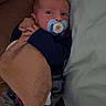 baby, pacifier, blanket, boy, couch, pillow, infant, clothing, sleepwear, cute, child, lying_down, indoor, comfort, hands, face, person, resting, cozy, young