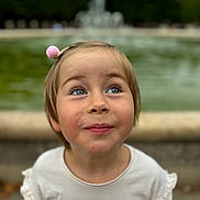 Mathilde a rejoint le concours — aidez-le/la à gagner de superbes lots ! child, portrait, blue_eyes, smile, hairpin, cup, outdoor, fountain, blurred_background, curious, cute, casual_clothing, young_child, daylight, happy, face, innocent, freckles, short_hair, nature